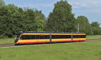 gelbe S-Bahn fährt durch Natur