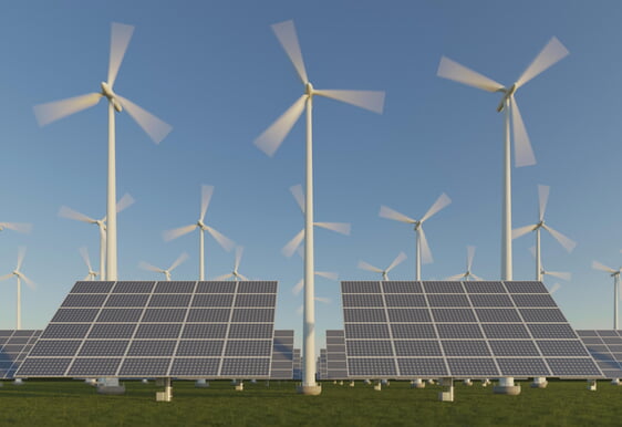 im Vordergrund große Photovoltaik-Panels, im Hintergrund einige Windräder