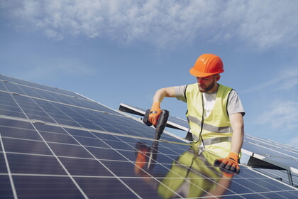 Ein Mann befestigt ein Solar-Modul auf einem Dach